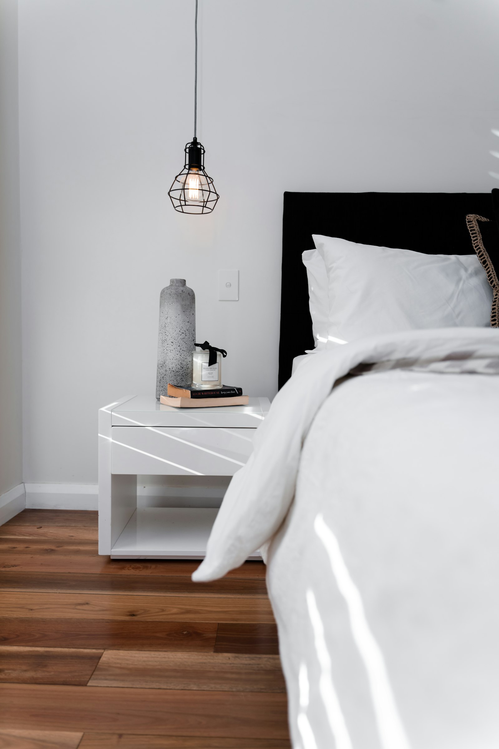 A bed made with white linen in daylight